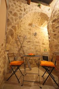 einen Tisch und zwei Stühle vor einer Steinmauer in der Unterkunft Il palazzetto del pescatore in Augusta