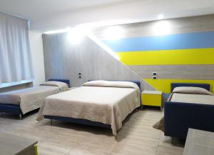 Habitación con 3 camas y pared colorida. en B&B Carrabs, en Battipaglia