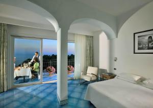 a bedroom with a bed and a table and a balcony at Hotel La Floridiana in Capri