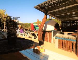 a patio with a grill and a table with a bell at Pili Pili Beach Cabanas in Sedgefield