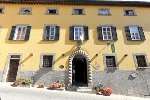 a yellow building with an arch doorway and windows at Antica Dimora Patrizia in Montecarlo