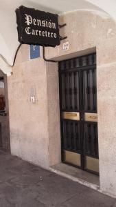 un edificio con una puerta con un cartel. en Pension Carretero, en Cáceres