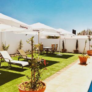 eine Terrasse mit weißen Sonnenschirmen, Tischen und Stühlen in der Unterkunft 5 Soles Hostal Rural in Carmona