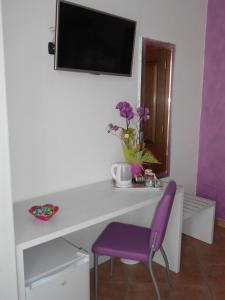 TV y escritorio blanco con silla morada. en Capital Bed Porto Cesareo, en Porto Cesareo