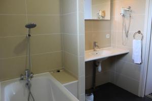 La salle de bains est pourvue d'un lavabo et d'une baignoire à côté d'un lavabo. dans l'établissement Hôtel Fleur de Lys Hazebrouck, à Hazebrouck