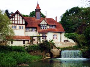a house next to a river with a waterfall at Chambre d'hôtes du Moulin de Landonvillers in Courcelles-Chaussy