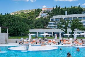 a pool with chairs and umbrellas in a hotel at Apartmani D & J with Heated Pool & Stunning Sea View in Orasac