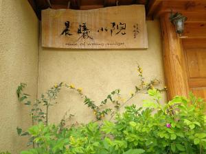 a sign on the side of a building with a plant at Courtyard Shangri-la 藏舍小院 in Shangri-La