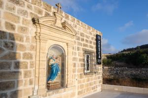 a statue of a woman on the side of a building at Cesca's Boutique Hotel in Xlendi
