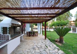 a pergola over a patio with a table and a grill at Filoxenia in Paralio Astros
