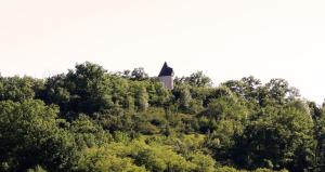 una torre en la cima de una colina con árboles en Moulin De Rouzé en Castelnaud-de-Gratecambe