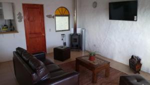 a living room with a leather couch and a television at Casa San Marcos El Tabo in El Tabo