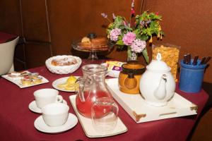 a table with a red table cloth with tea pots and cups at La Torre-1984 in Sarnelli