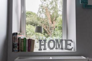 una ventana con una señal de casa frente a una estantería de libros en One Night Zielona Góra, en Zielona Góra