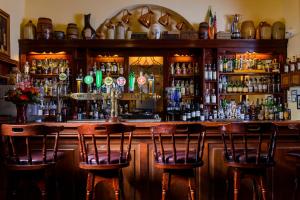 a bar with three bar stools in front at Dingle Benners Hotel in Dingle