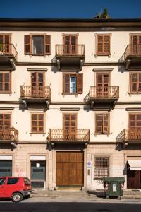 ein Gebäude mit Balkon und einem roten Auto, das vor der Tür geparkt ist in der Unterkunft Old Town Torino in Turin