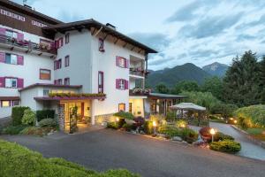 a large white building with a lot of flowers at Hotel Latemar in Castello di Fiemme