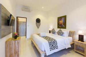 a bedroom with a large white bed and a flat screen tv at Amerta Seminyak in Seminyak