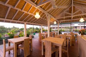 a restaurant with wooden tables and chairs on a deck at Amerta Seminyak in Seminyak