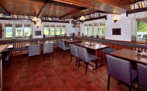 ein Restaurant mit Holztischen, Stühlen und Fenstern in der Unterkunft Chata Orlik - all inclusive & wellness in Pec pod Sněžkou