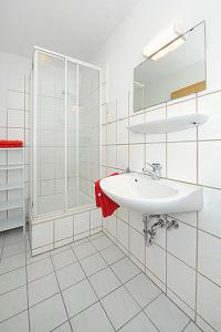 ein weißes Bad mit einem Waschbecken und einer Dusche in der Unterkunft Reit- und Ferienhof Maack in Neuharlingersiel
