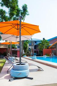 a table with an umbrella and a tire next to a pool at Maxwell Court Apartments in Accra