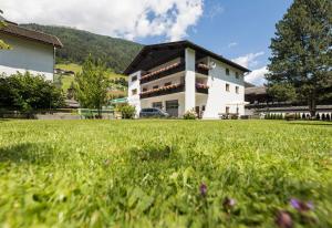 a large building with a grass field in front of it at Ferienwohnung Haus Zyka in Neustift im Stubaital