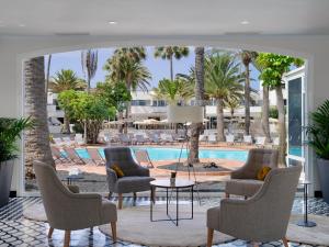 a lobby with chairs and a pool with palm trees at H10 Ocean Dunas - Adults Only in Corralejo