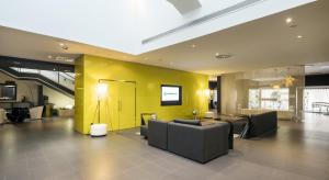 uma sala de estar com um sofá e uma parede amarela em Ilunion Bel-Art em Barcelona