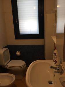 a bathroom with a sink and a toilet and a window at Valentina Holiday House in Mascali +8 photos