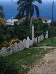 a white fence with a palm tree and the ocean at My-Places Montego Bay Vacation Home in Montego Bay