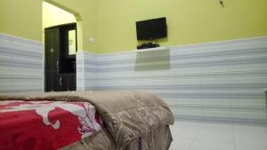 1 dormitorio con pared y TV de pantalla plana en ZONA Homestay en Selong