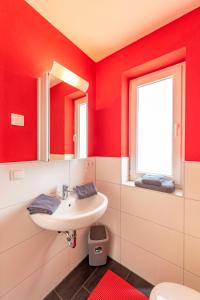 ゲーレンにあるVilla Mia Whg 4 mit Terrasse EG 1 Raum Wohnungの赤い壁のバスルーム(洗面台、窓付)