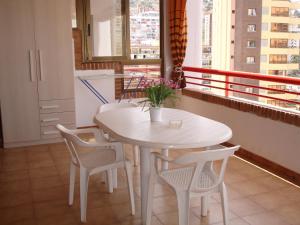 una mesa y sillas blancas en una habitación con ventana en Loix Mar - Zand Properties, en Benidorm