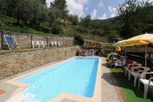 a large swimming pool with chairs and an umbrella at Hotel Archimede in Reggello