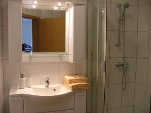 a bathroom with a sink and a shower with a mirror at Hotel Thule in Carolinensiel +40 photos