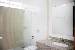 a bathroom with a toilet and a sink and a shower at Motel Passport in Guaratinguetá