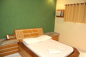 a small bed in a room with a green wall at Motel Passport in Guaratinguetá