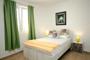 a bedroom with a bed with green curtains and a window at Apartments Mirko in Ulcinj