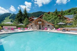 a swimming pool at a resort with mountains in the background at Hotel Eterlou in M&eacute;ribel