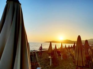 a group of umbrellas and chairs on a beach with the sunset at Magicomar Hotel in Ascea