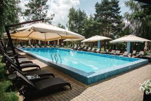 a large swimming pool with chairs and umbrellas at Загородный отельно-ресторанный комплекс "Четыре сезона" in Pylypovychi