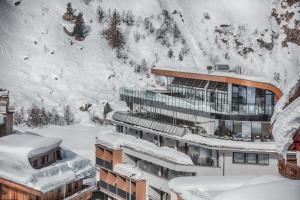 un edificio coperto di neve di fronte a una montagna di Josl Mountain Lounging Hotel - Adults only! a Obergurgl
