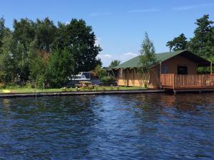 a cabin on the shore of a body of water at Glamping Amsterdam "only to be reached by boat" in Baambrugse Zuwe
