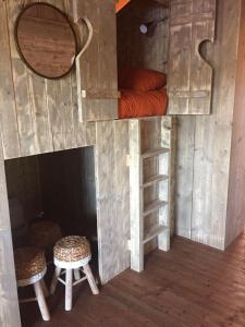 a tree house with a bed and two stools at Glamping Amsterdam "only to be reached by boat" in Baambrugse Zuwe