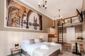 a bedroom with a large white bed and a kitchen at Apartamenty L5 in Krakow