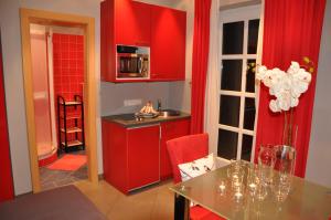 a kitchen with red cabinets and a table in a room at Appartementhaus Grill in Strobl
