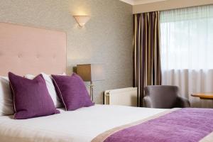 a hotel room with a large bed with purple pillows at Lea Marston Hotel in Lea Marston