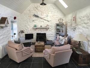 a living room with two chairs and a stone wall at The Old Beach Cottage, Achill in Doogort