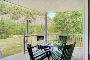 eine Terrasse mit einem Tisch und Stühlen auf einer Veranda in der Unterkunft Entre roc et montagne in LʼAnse-Saint-Jean